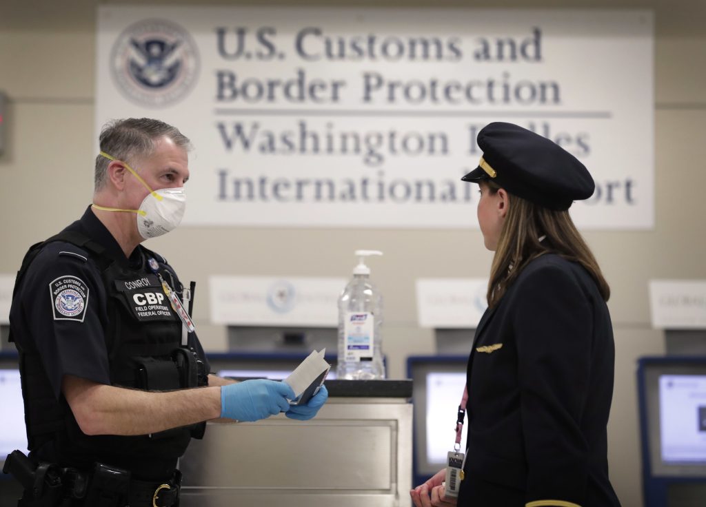 An officer with U.S. Customs and Border Protection Office of Field Operations reviews travel the documents of an arriving international airline pilot at Dulles International Airport in Dulles, Va., March 18, 2020. Photo: Prachatai on Flickr,