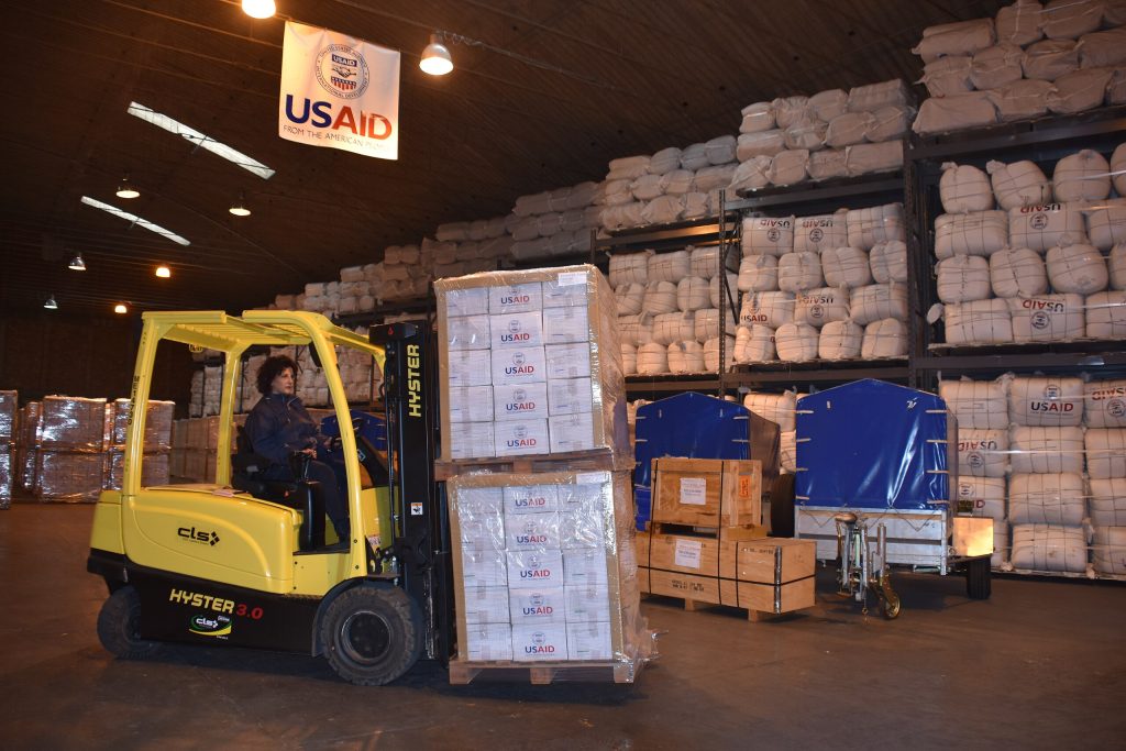 Carmensita Caroccia inside the Office of Foreign Disaster Assistance warehouse at Camp Darby moving emergency supplies later shipped to Mozambique. Photo: U.S. Army USAG-V by Chiara Mattirolo on Wikimedia Commons.