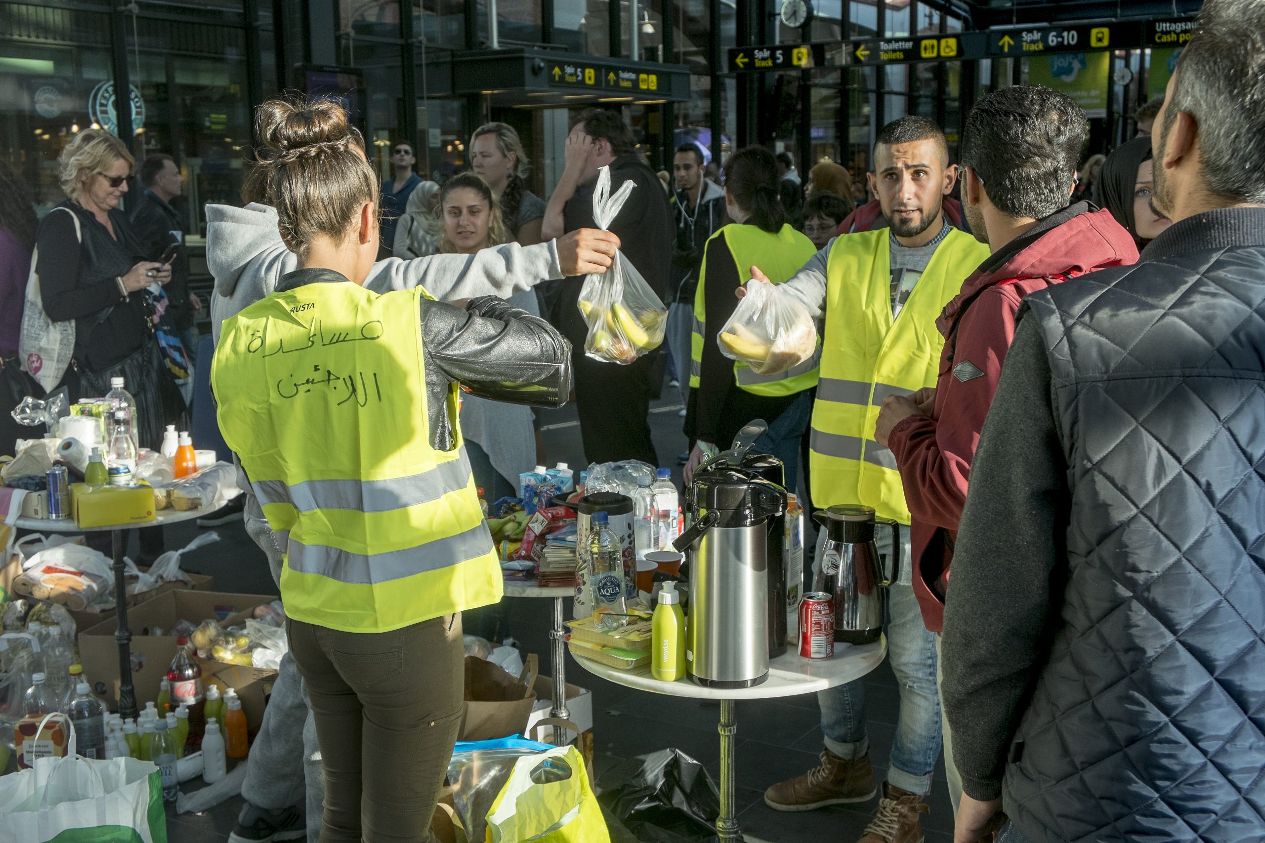 Volunteers offer food and help with train tickets to asylum seekers arriving on Öresund trains from Denmark in the waiting hall at Malmö Central Station. Photo: News Øresund / Johan Wessman / Wikimedia Commons. CC BY 3.0