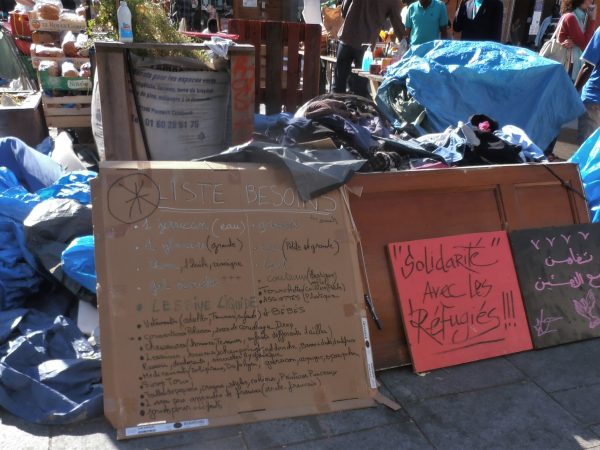 "Solidarity with Refugees" Sign in Paris, Halle Pajol. Photo source: Jeanne Menjoulet / Flickr, CC BY 2.0