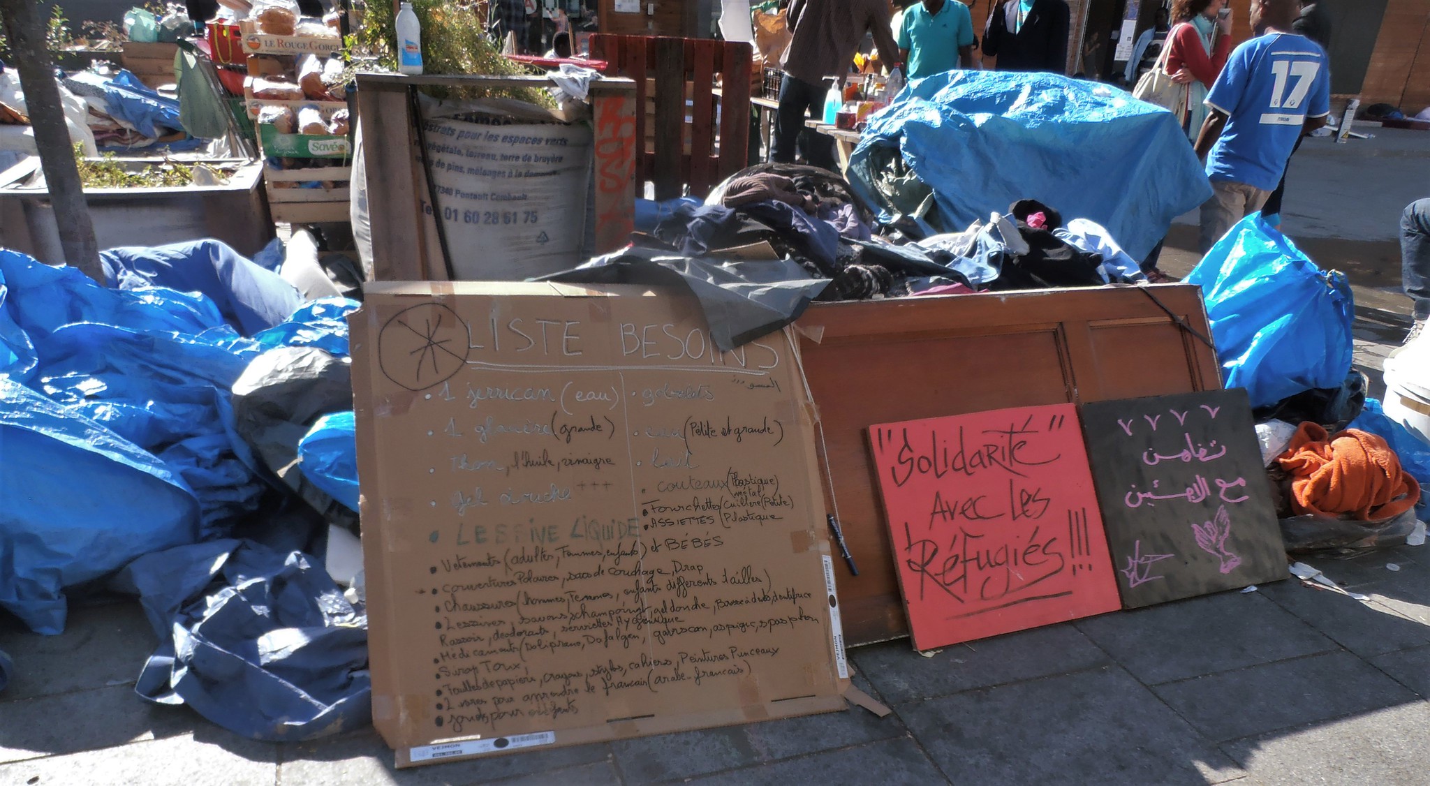 "Solidarity with Refugees" Sign in Paris, Halle Pajol. Photo source: Jeanne Menjoulet / Flickr, CC BY 2.0