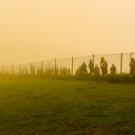 Trabzon / Turkey - August 07 2019: Silhouette of people walk behind the wire in a cold day under fog. Photo source: Adobe Stock..
