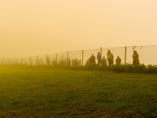 Trabzon / Turkey - August 07 2019: Silhouette of people walk behind the wire in a cold day under fog. Photo source: Adobe Stock..