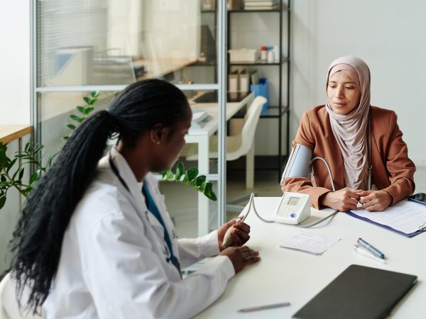 A woman in a hijab receives advice from a doctor. Source: Shutterstock.